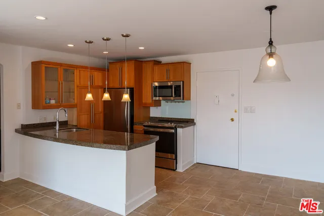a kitchen with stainless steel appliances granite countertop a sink and a refrigerator
