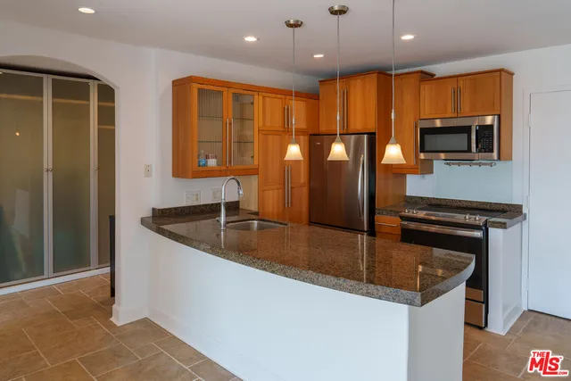 a kitchen with stainless steel appliances granite countertop a sink and a refrigerator