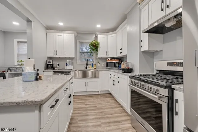 a large kitchen with stainless steel appliances granite countertop a stove a sink and white cabinets