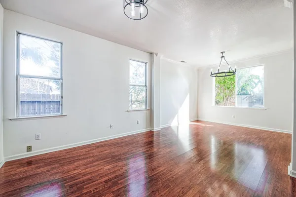 an empty room with wooden floor fireplace and windows