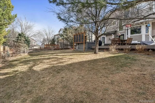 a backyard of a house with large trees and outdoor seating