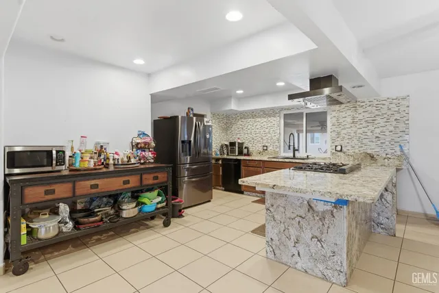 a kitchen with stainless steel appliances kitchen island granite countertop a refrigerator and a stove