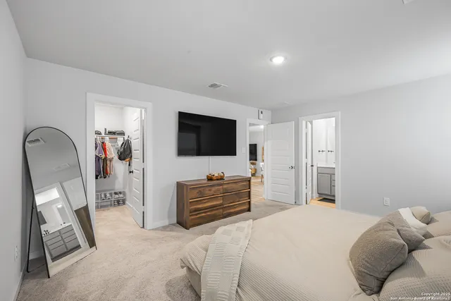 a bedroom with a bed and a flat tv screen on dresser