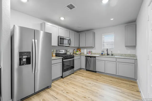 a kitchen with granite countertop a refrigerator stove top oven and sink