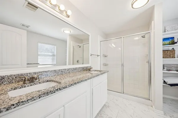 a bathroom with a granite countertop sink a mirror and a shower
