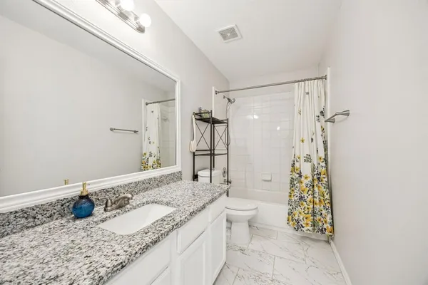 a bathroom with a granite countertop sink a toilet and shower