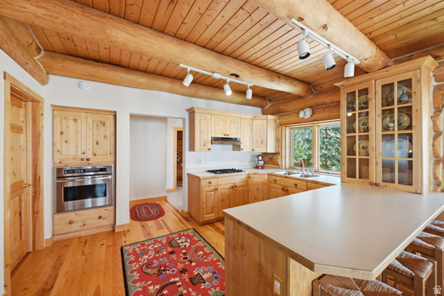 11192 Maple Road, Unit 7 Heber City, UT 84032 - Photo 14 of 51 Natural wood ceiling and exposed beams, wood-finish flooring, custom wood cabinetry, stainless steel built-in oven, and a built-in kitchen island with seating