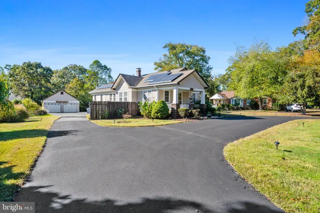 a front view of a house with a yard and large trees