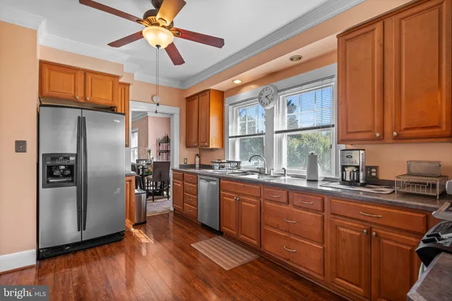 a kitchen with stainless steel appliances granite countertop a refrigerator a sink dishwasher a stove and white countertops with wooden floor