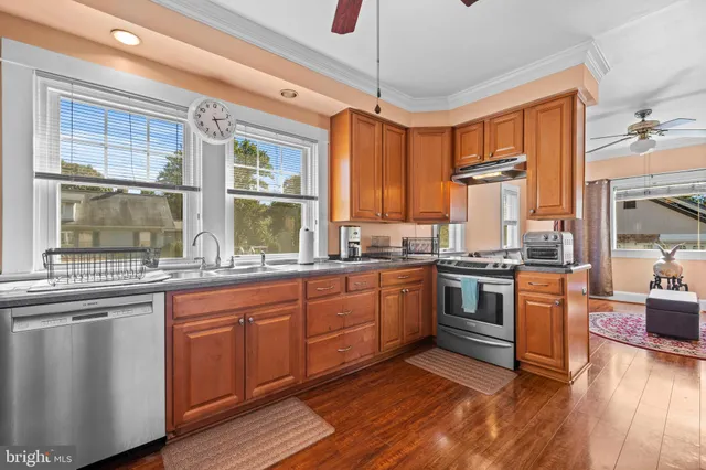 a kitchen with stainless steel appliances granite countertop hardwood floor sink stove and wooden cabinets