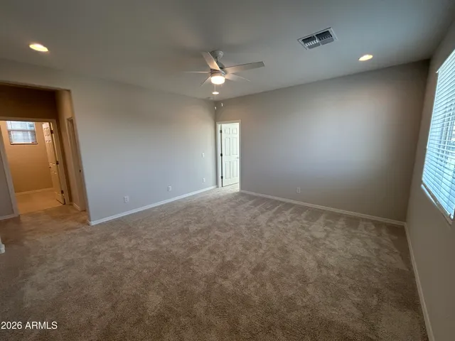 an empty room with a chandelier fan and windows