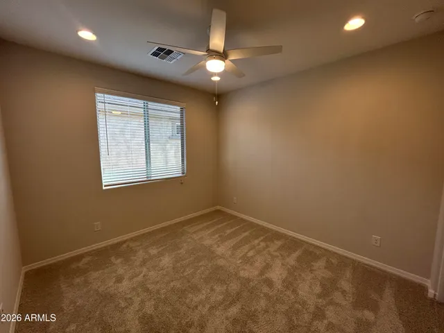 an empty room with a ceiling fan and window