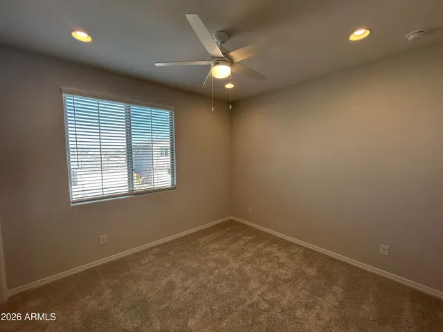 an empty room with a ceiling fan and window