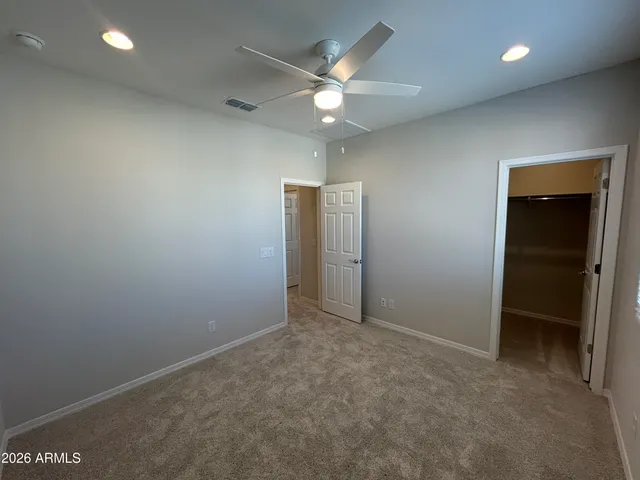 an empty room with closet and a ceiling fan