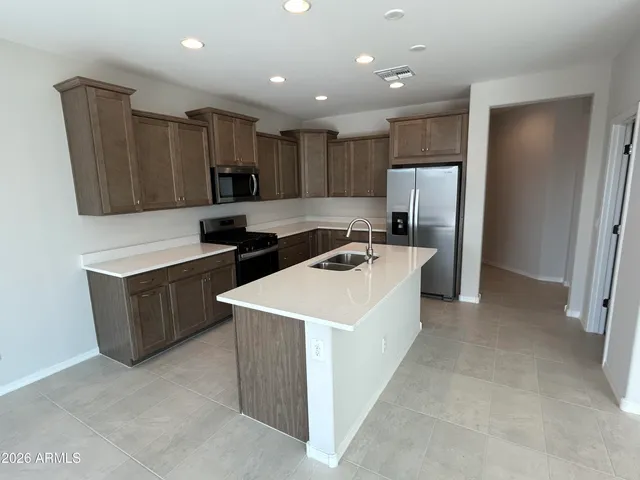 a kitchen with a refrigerator a stove top oven a sink and cabinets