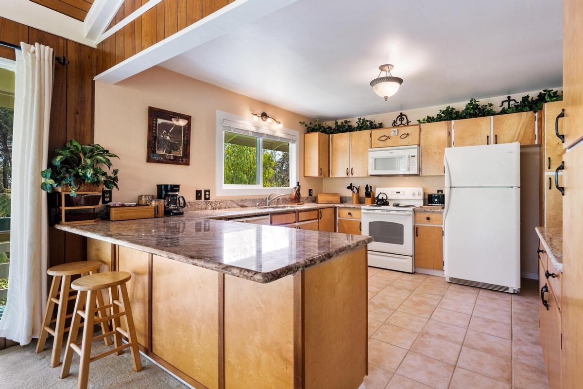 19-4252 Wright Road Volcano, HI 96785 - Photo 2 of 30 a kitchen with granite countertop a refrigerator a stove a sink a dining table and chairs