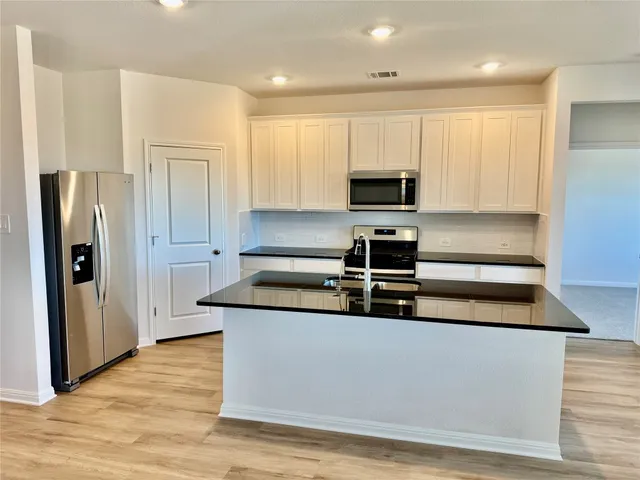a view of kitchen with stainless steel appliances granite countertop a stove a refrigerator and a granite counter tops with wooden floors