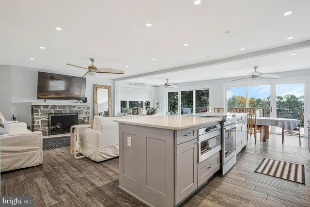a open kitchen with stainless steel appliances granite countertop a stove top oven a sink dishwasher a dining table and chairs with wooden floor