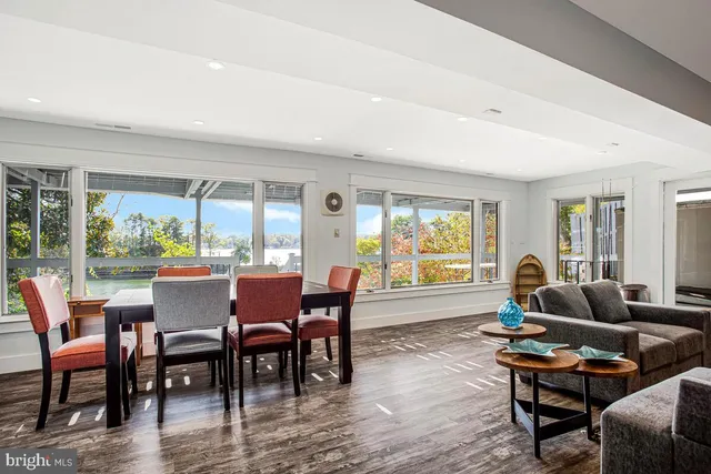 a dining room with furniture large windows and wooden floor