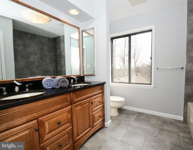 7307 Hooking Road McLean, VA 22101 - Photo 28 of 29 a bathroom with a granite countertop toilet a sink and a large mirror