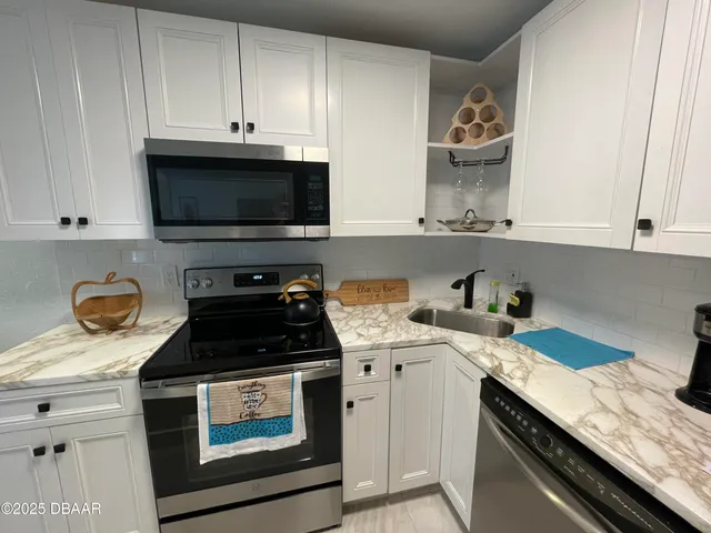 a kitchen with granite countertop a sink a stove and cabinets