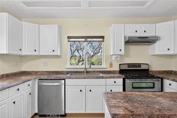 a kitchen with stainless steel appliances granite countertop a sink and dishwasher a stove top oven with white cabinets