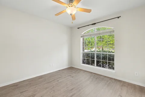 an empty room with windows and fan