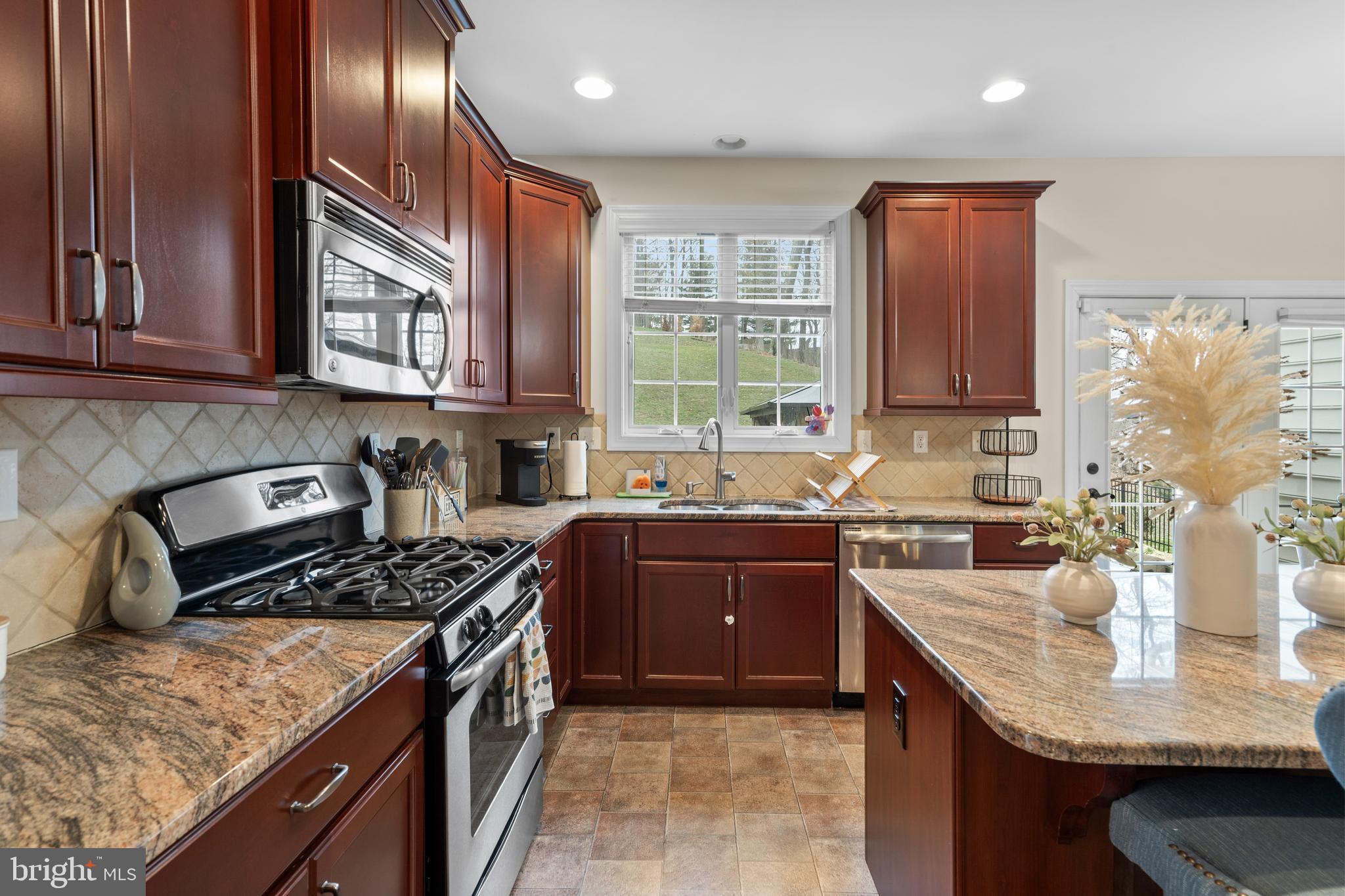 776 Barry Drive Springfield, PA 19064 - Photo 16 of 44 a kitchen with stainless steel appliances granite countertop a stove a sink dishwasher and a refrigerator with wooden cabinets