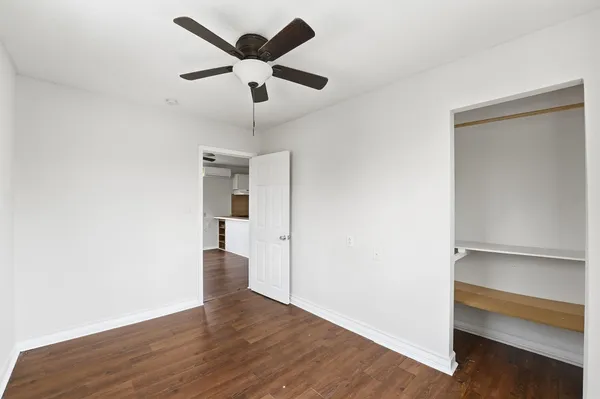 an empty room with wooden floor and ceiling fan