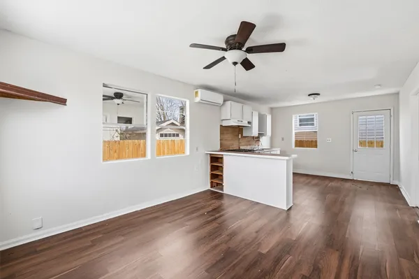 a view of a kitchen with wooden floor a ceiling fan and windows