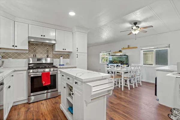 a kitchen with stainless steel appliances granite countertop a stove and a white cabinets