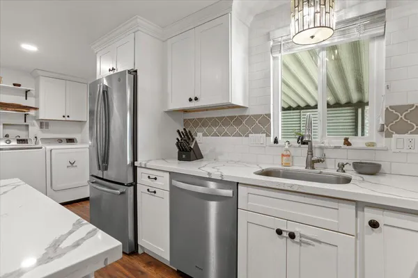 a kitchen with white cabinets wooden floor and stainless steel appliances