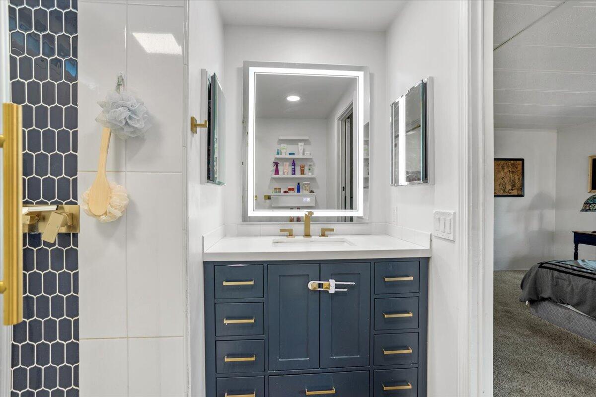 5700 Via Real, Unit 106 Carpinteria, CA 93013 - Photo 25 of 26 a bathroom with a granite countertop sink a mirror and a shower