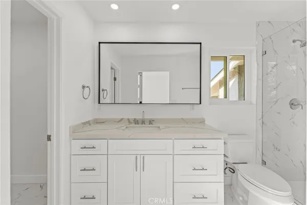 a bathroom with a granite countertop sink vanity mirror next to a toilet