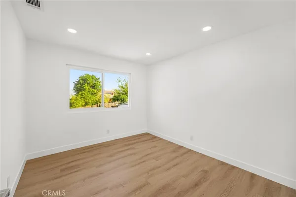 an empty room with wooden floor and window