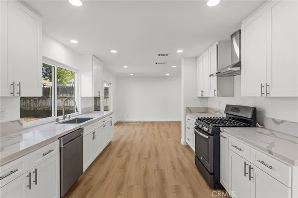 a large kitchen with stainless steel appliances lots of counter space and wooden floor