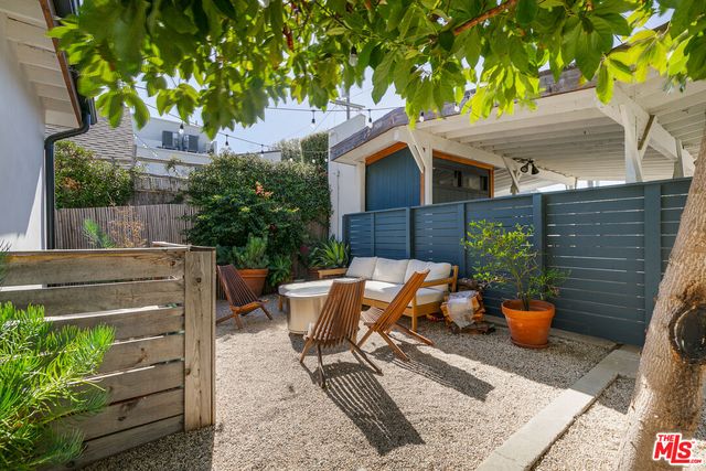 a view of a patio with table and chairs potted plants and a large tree