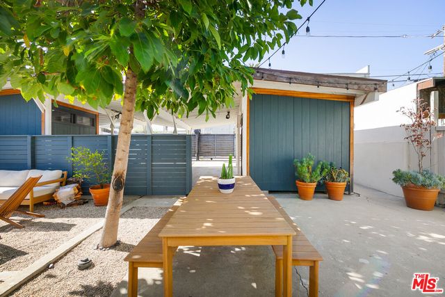 a view of a patio with table and chairs potted plants and a large tree