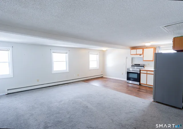 an empty room with windows and kitchen view