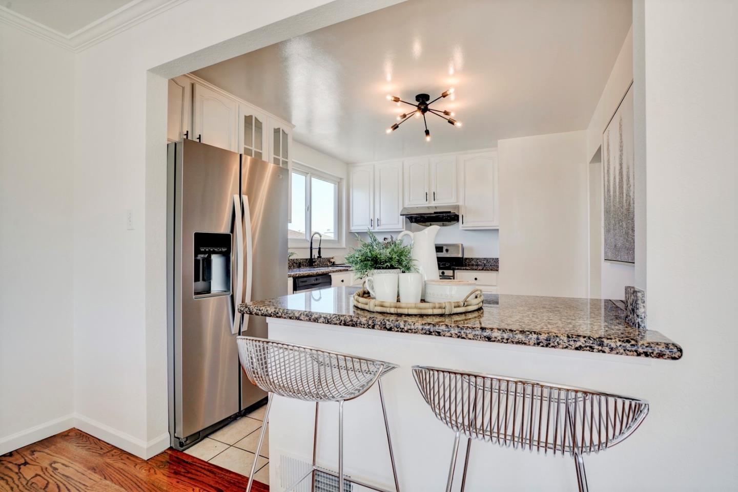 391 Imperial Drive Pacifica, CA 94044 - Photo 16 of 60 a kitchen with granite countertop a refrigerator a stove a sink and chairs