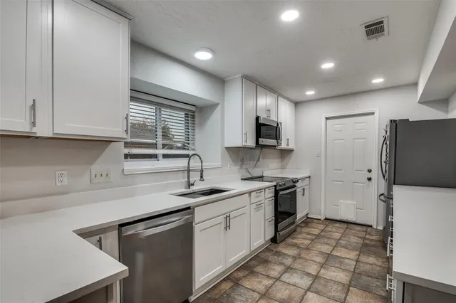 a kitchen with a sink a stove a refrigerator and cabinets