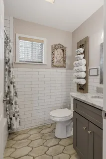 a bathroom with a granite countertop toilet a sink a mirror and shower curtain