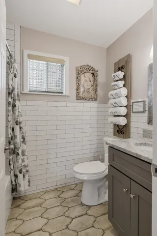 a bathroom with a granite countertop toilet a sink a mirror and shower curtain