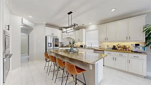 a kitchen with stainless steel appliances granite countertop a sink a stove a dining table and chairs