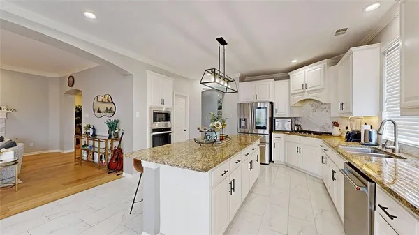 a large kitchen with granite countertop a large island in the center and stainless steel appliances