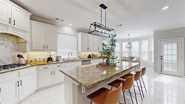 a kitchen with stainless steel appliances granite countertop a sink a stove and chairs