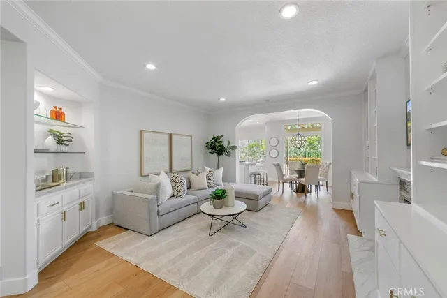 a large living room with stainless steel appliances kitchen island granite countertop a dining table chairs in it and wooden floors