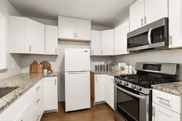a kitchen with granite countertop white cabinets and stainless steel appliances