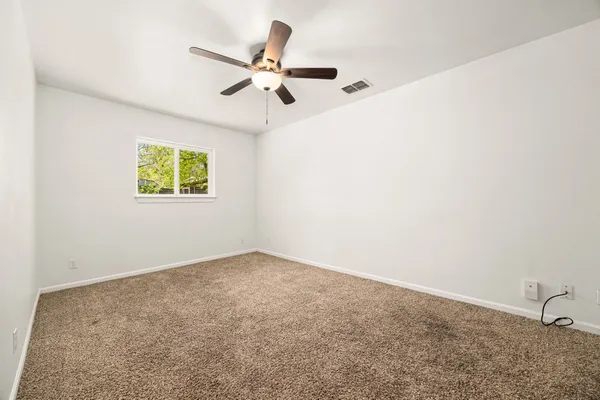 an empty room with windows and fan