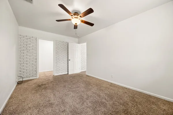 an empty room with a chandelier fan and windows